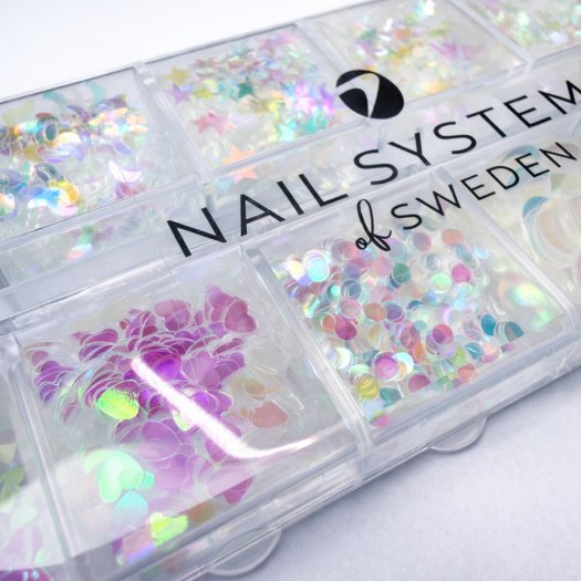 Ask med 12 tunna, transparenta paljetter i mixade former och storlekar. Skiftande finish, enkla att forma mot nageln och perfekt