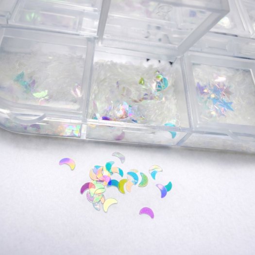 Ask med 12 tunna, transparenta paljetter i mixade former och storlekar. Skiftande finish, enkla att forma mot nageln och perfekt