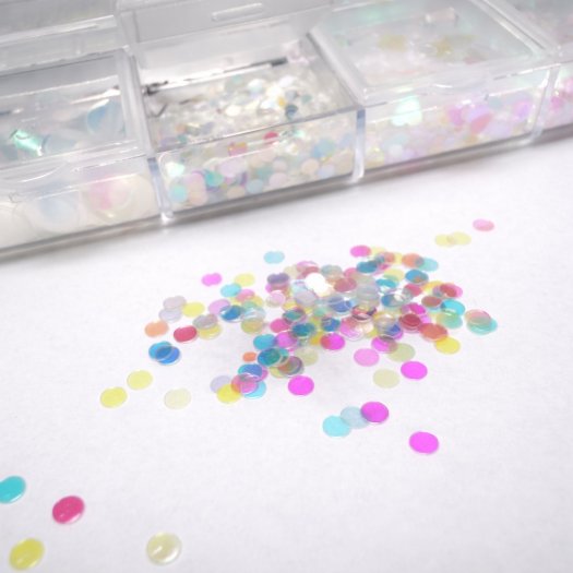 Ask med 12 tunna, transparenta paljetter i mixade former och storlekar. Skiftande finish, enkla att forma mot nageln och perfekt