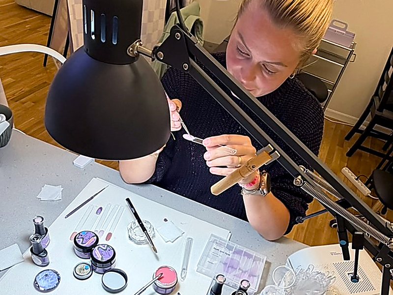 Student working on nails at her desk with guidance